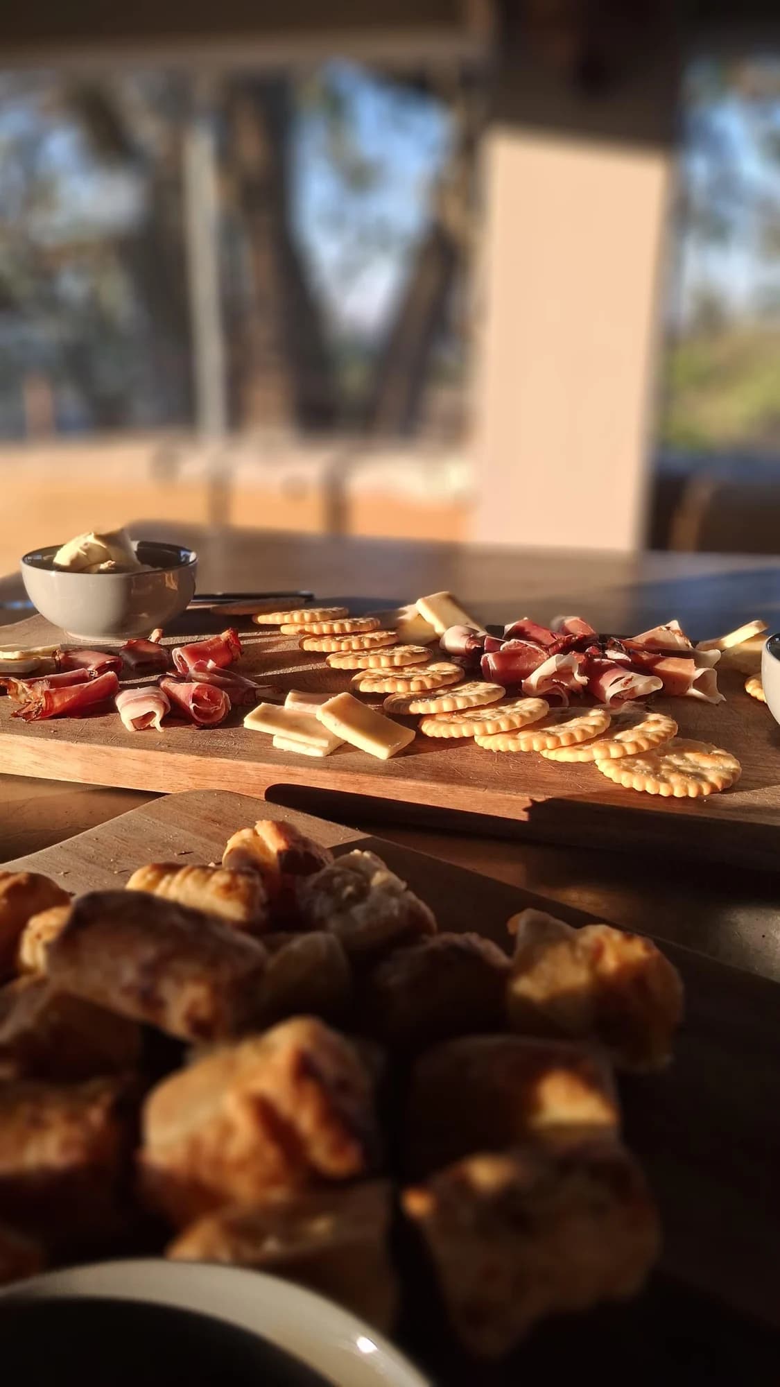 A platter of cheese, crackers and cured meat on a wooden table