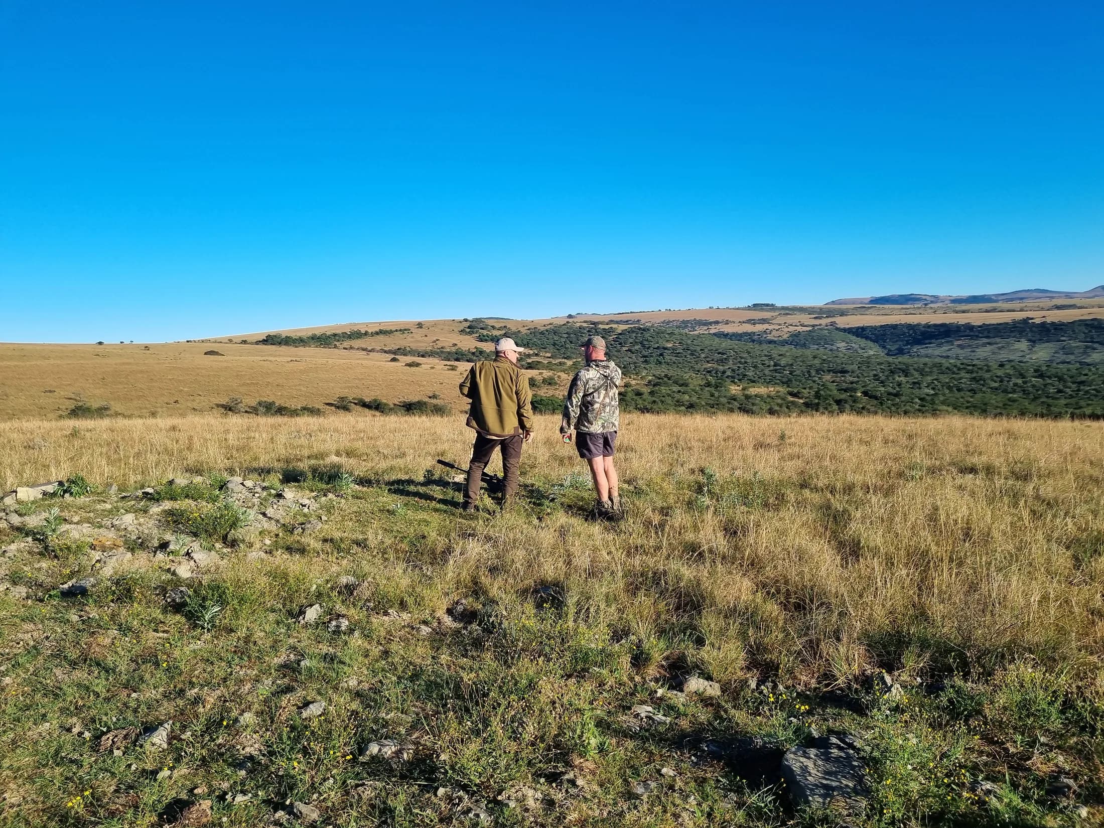 Two people walking through wide open grassland
