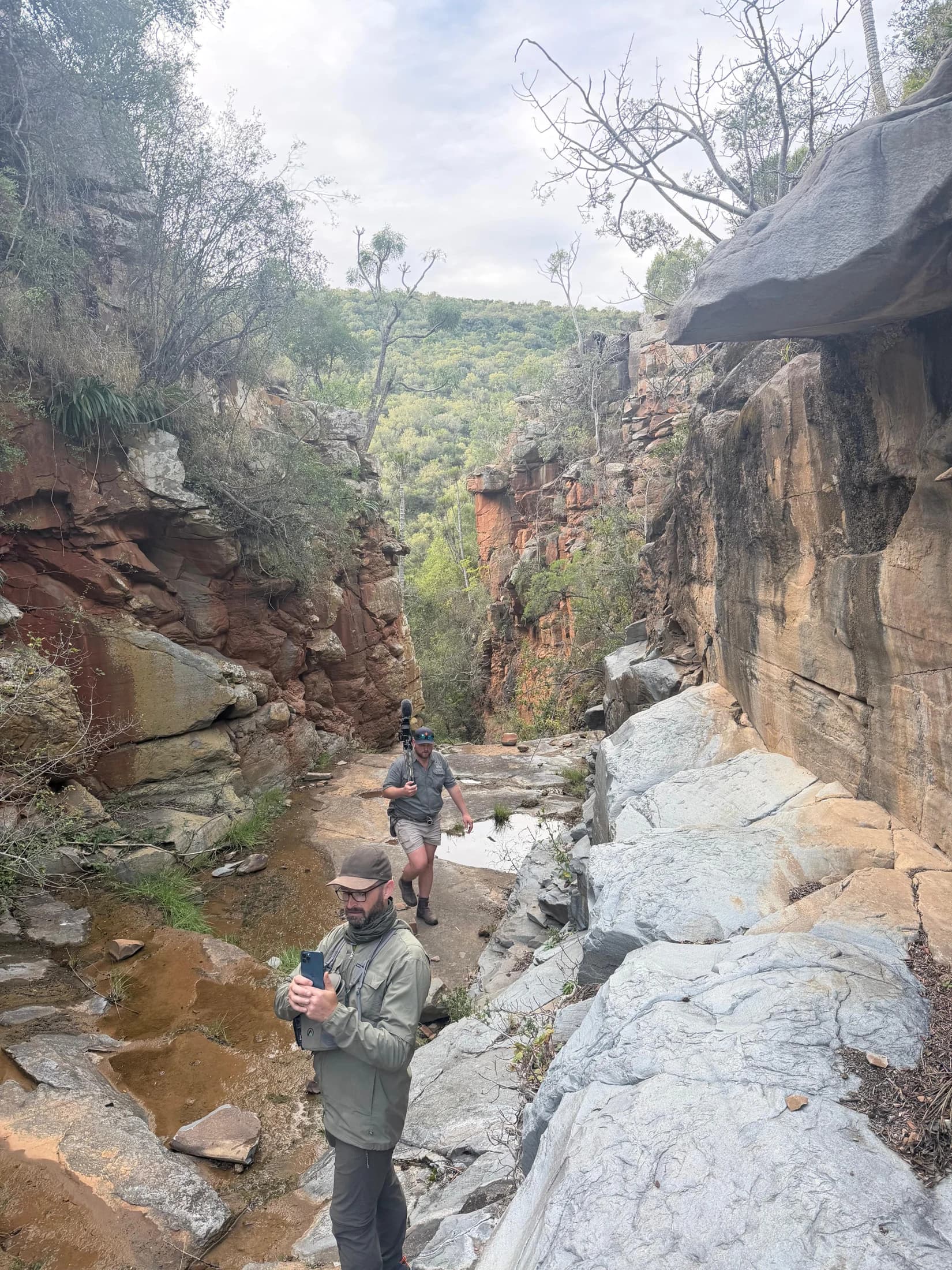 Two hunters walking through a rocky river gorge