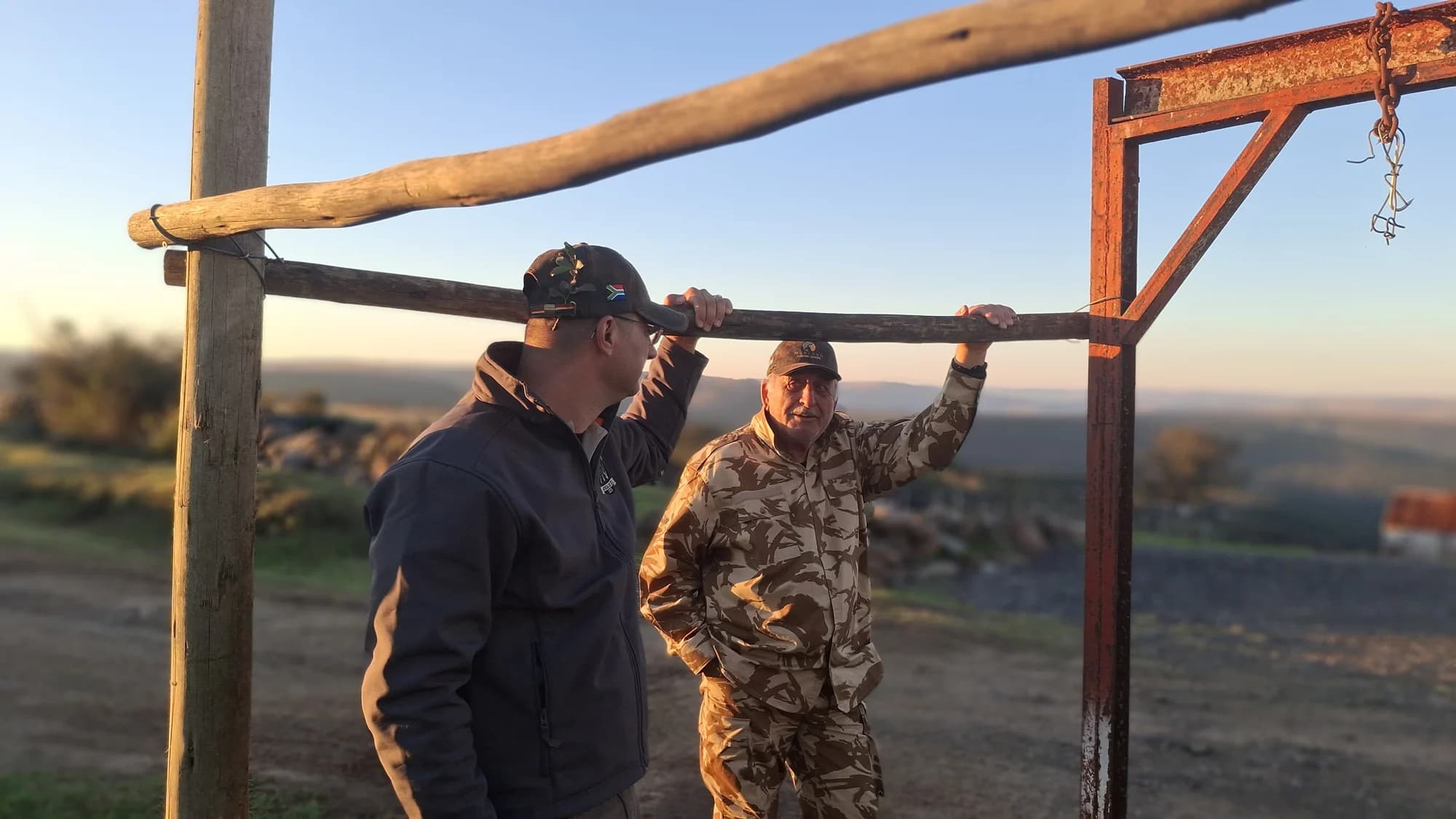 Two people talking beside a wooden rail and metal hoist outdoors