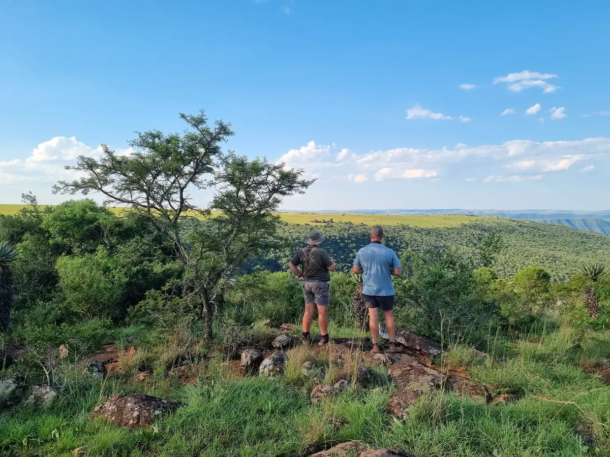 Two people looking across a wide green valley